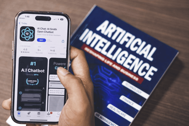 Smartphone displaying AI chatbot app with artificial intelligence book in background.